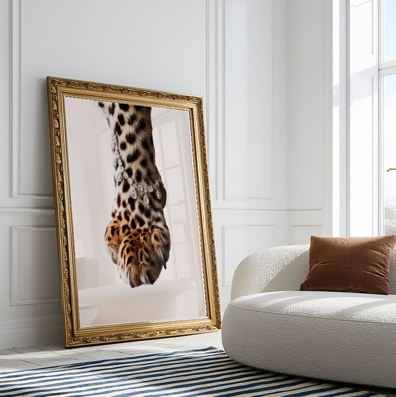 May include: A close-up of a leopard's paw with a diamond necklace around it. The paw is in a gold frame and the background is a light pink.