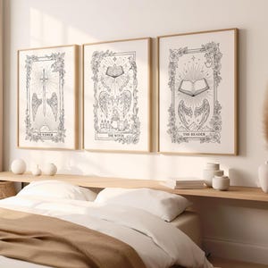 Puede incluir: Tres impresiones artísticas enmarcadas con marcos dorados. Cada impresión presenta una ilustración en blanco y negro con elementos florales y celestiales. Las impresiones están etiquetadas como "The Warrior", "The Witch" y "The Reader".