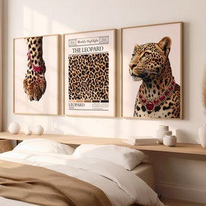 以下が含まれることがあります： ヒョウ柄をテーマにした額装されたプリントが3枚。左側のプリントは、赤い宝石のブレスレットをつけたヒョウの足の裏のクローズアップ。中央のプリントは、カラーパレット付きのヒョウ柄パターン。右側のプリントは、赤い宝石のネックレスをつけたヒョウ。中央のプリントには、「Weekly Highlight」と「THE LEOPARD」の文字が印刷されています。