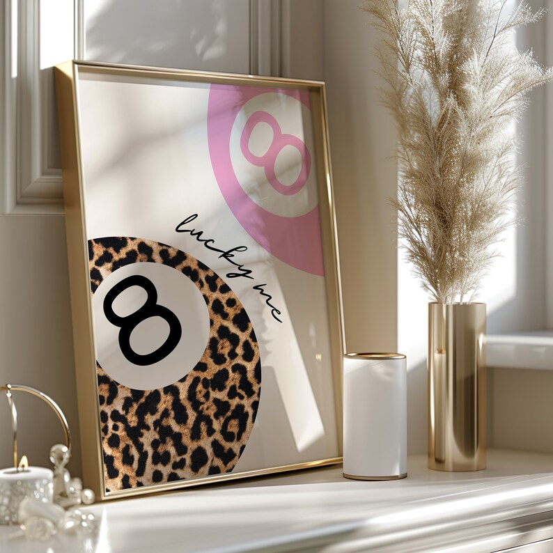 Puede incluir: Una impresi&oacute;n enmarcada en dorado con un dise&ntilde;o de bola 8 rosa y blanca y el texto "lucky me". La bola 8 est&aacute; rodeada de un patr&oacute;n de estampado de leopardo.