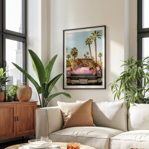 May include: A pink vintage car with a leopard lying on the bonnet. The car has a California number plate that reads "2FLT842". The car is parked in front of palm trees against a blue sky.