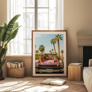 May include: A pink vintage car with a leopard lying on the bonnet. The car has a number plate that reads "2FLT842". The car is parked in front of a palm tree lined street.