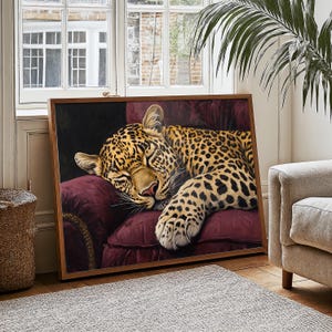 May include: A framed painting of a leopard sleeping on a plush, burgundy velvet armchair. The leopard's fur is a mix of brown, black, and yellow spots. The painting is set against a dark background.