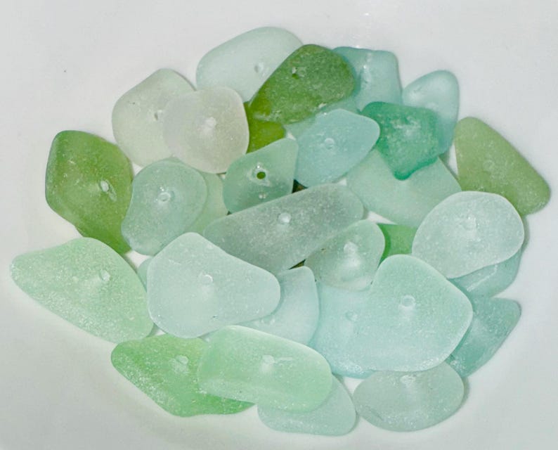 Peut inclure: Un ensemble de perles en verre de mer dans des tons de vert et de bleu. Les perles sont lisses et ont un aspect givr&eacute;. Elles sont parfaites pour la fabrication de bijoux ou d'autres projets d'artisanat.