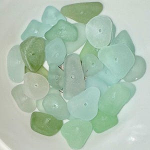 Peut inclure: Une collection de perles de verre de mer dans diff&eacute;rentes nuances de vert et de bleu. Les perles sont lisses et ont un trou au centre, ce qui les rend adapt&eacute;es &agrave; la fabrication de bijoux ou &agrave; d'autres travaux manuels.