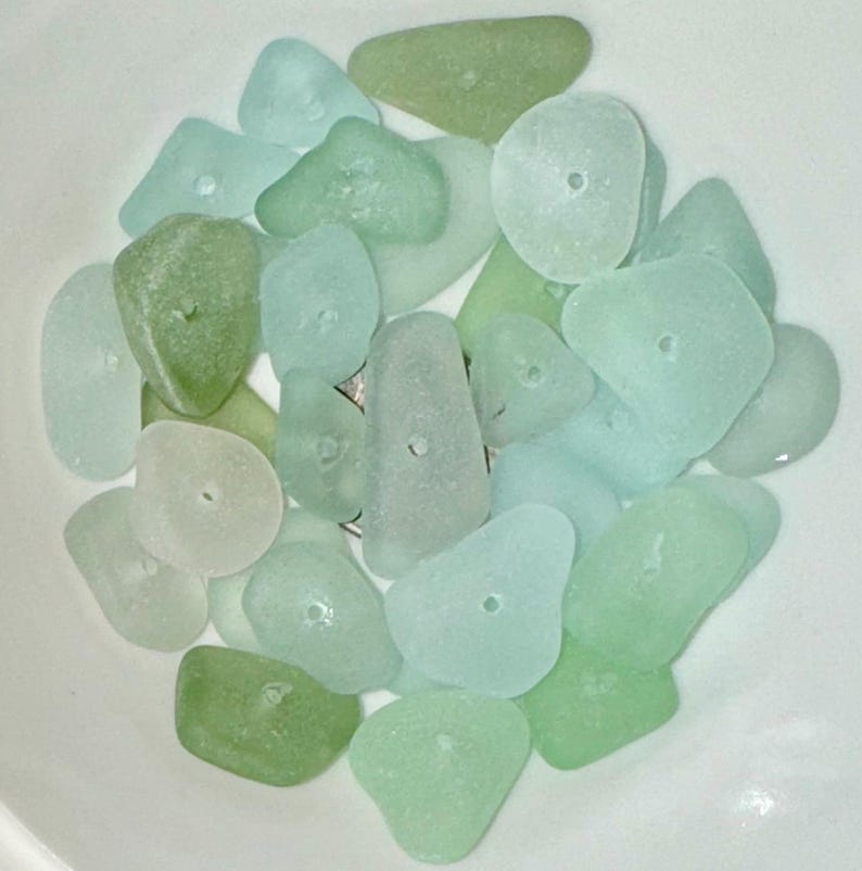 Peut inclure: Une collection de perles de verre de mer dans diff&eacute;rentes nuances de vert et de bleu. Les perles sont lisses et ont un trou au centre, ce qui les rend adapt&eacute;es &agrave; la fabrication de bijoux ou &agrave; d'autres travaux manuels.