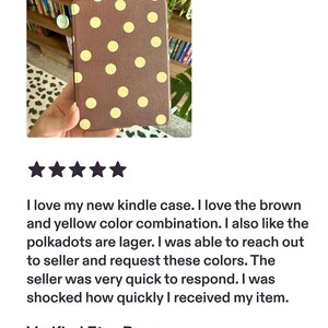 May include: A rectangular e-reader case featuring a brown base color with a repeating pattern of large, light yellow circular polka dots. The case has a textured surface and a slim, flat profile designed to protect a handheld electronic device.