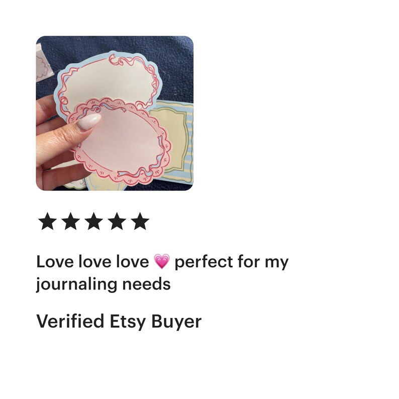 May include: A hand holding two oval-shaped, decorative paper labels with a pink and red border. The labels have a light pink center and a scalloped edge. Additional labels with blue and yellow borders are visible.