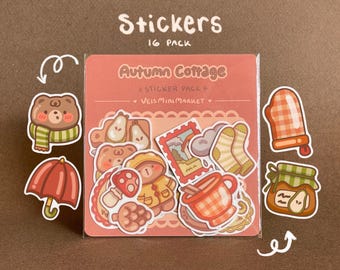 May include: A pack of 16 stickers with an autumn cottage theme. The stickers feature illustrations of a bear, umbrella, pears, socks, a stamp, a mug, a mitten, and a jar of jam. The text "Stickers" and "Autumn Cottage" are visible.