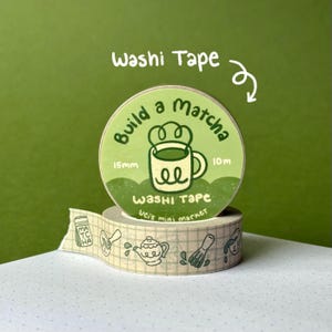 May include: A roll of light green washi tape featuring a circular label that reads Build a Matcha, 15mm, 10m, and Vei's mini market. The tape displays a repeating pattern of matcha-themed illustrations including a jar, whisk, and teapot.