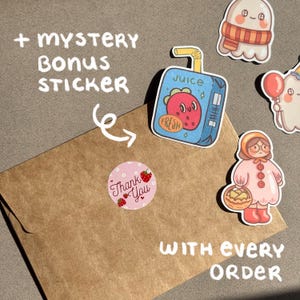May include: An assortment of colorful stickers, including a juice box with a strawberry design, a ghost with a scarf, and a girl with a basket. A brown envelope is shown with a pink "Thank You" sticker and text that reads "+ Mystery Bonus Sticker" and "With Every Order".