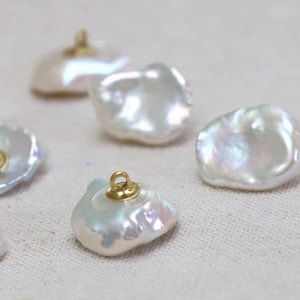 Op de afbeelding: Iridescent witte barok parel hangers met goudkleurige baleinen. De parels hebben onregelmatige vormen en een glanzend oppervlak, dat licht reflecteert. Ideaal voor het maken van sieraden.