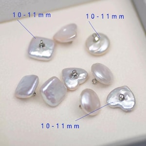 May include: Assortment of white, irregular-shaped pearl buttons, each with a metal shank. The buttons vary in shape, including square, round, heart, and oval. Text indicates the buttons are 10-11 mm in size.