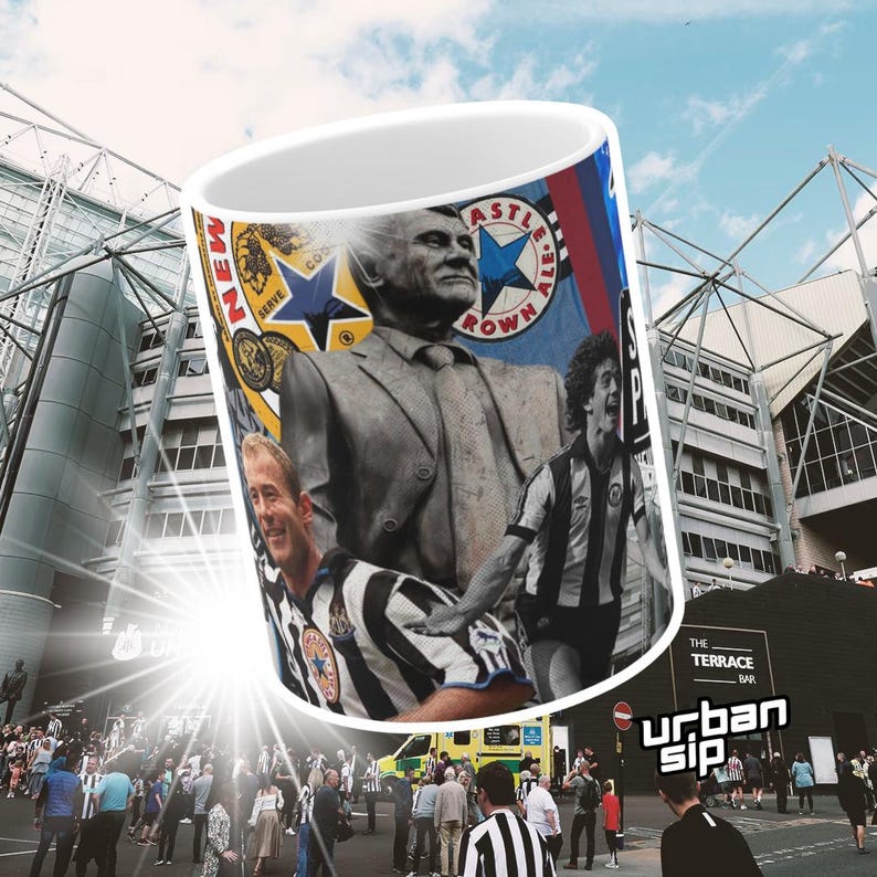 May include: A white ceramic mug with a colorful design featuring a soccer player, a statue of a man, and a soccer team logo. The mug has the words "Newcastle Brown Ale" and "The Terrace Bar" printed on it.
