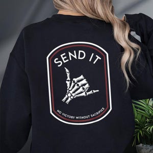 a woman wearing a black sweatshirt with the words send it on it