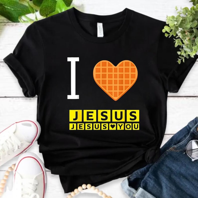 A black t-shirt with a heart-shaped waffle and the text "I ♥ JESUS JESUS YOU" printed on it, along with a pair of sneakers and a pair of jeans.