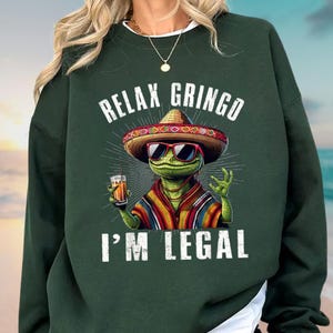 a woman wearing a green sweatshirt that says relax grino i'm legal