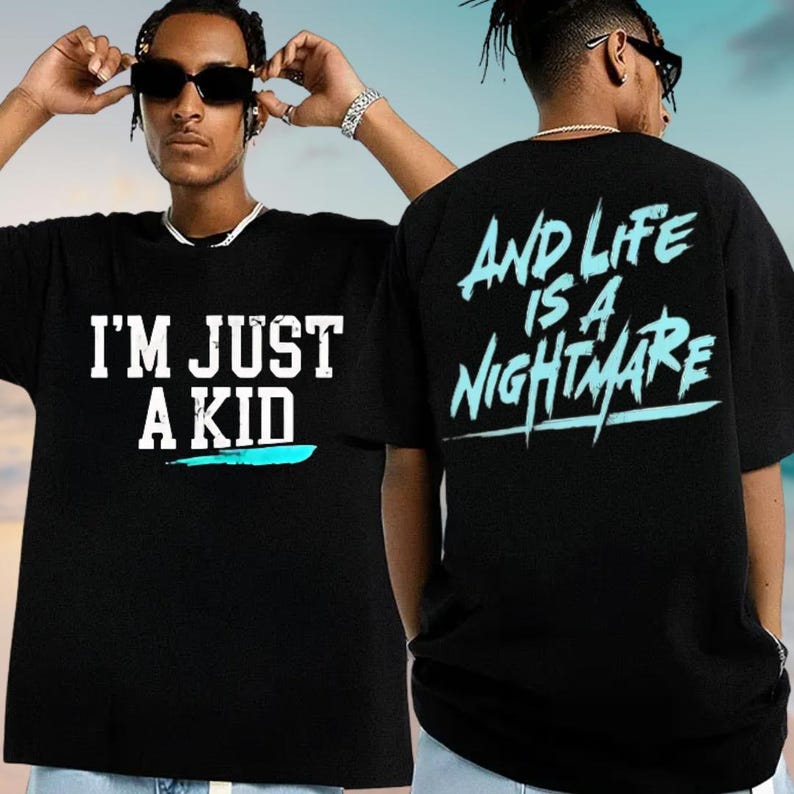 A man wearing a black t-shirt with the text "I'M JUST A KID" and "AND LIFE IS A NIGHTMARE" printed on it.