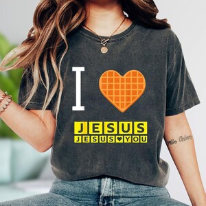 A person wearing a gray t-shirt with a heart-shaped graphic and text printed on it.