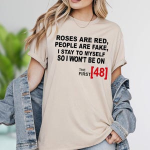 A woman wearing a beige t-shirt with text printed on it.