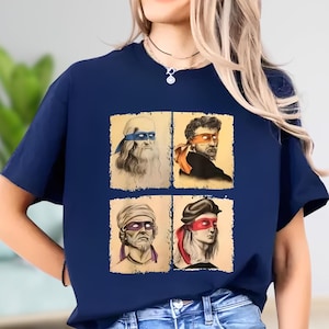 A woman wearing a blue t-shirt with four different portraits of men, each with distinct facial expressions and hairstyles.