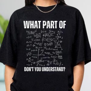 May include: A black short-sleeved t-shirt featuring white text that reads WHAT PART OF at the top and DON'T YOU UNDERSTAND? at the bottom, with a dense collection of white mathematical formulas and geometric equations printed in the center.