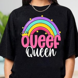 May include: Black sweatshirt featuring a colorful rainbow design with the words "Queef Queen" in pink and white. The rainbow includes purple, teal, yellow, and pink arches, with gold stars and a crown.