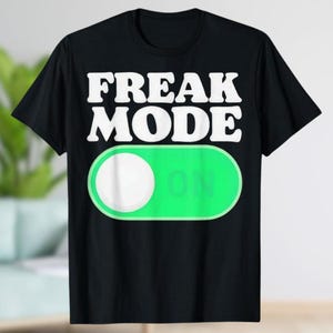 May include: Black t-shirt with the words "FREAK MODE" in white block letters above a green "ON" switch graphic. The switch has a white circle and the word "ON" in green.