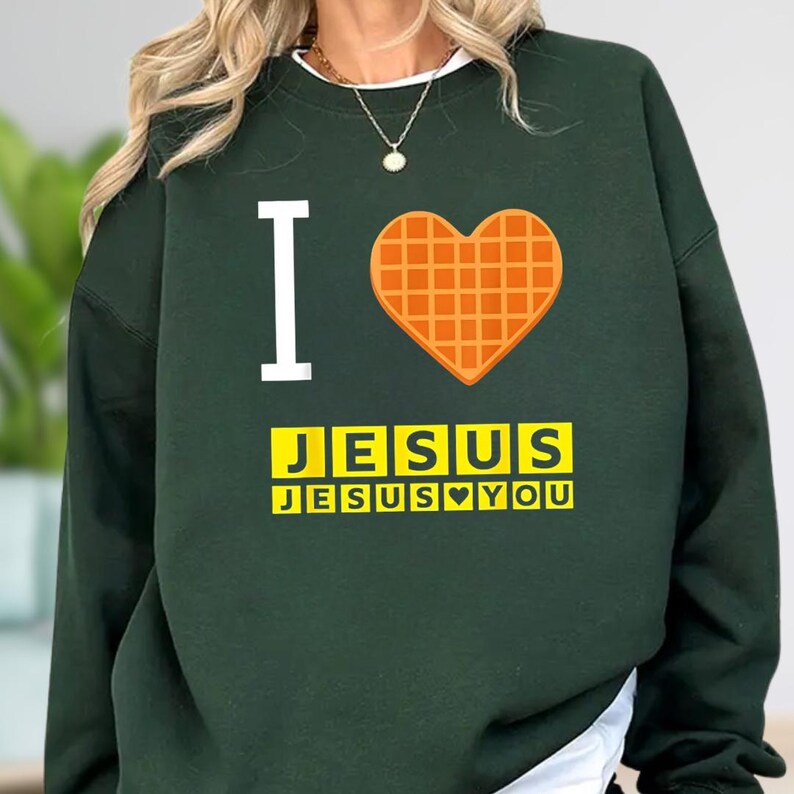 A person wearing a green sweatshirt with a heart-shaped graphic and text printed on it.