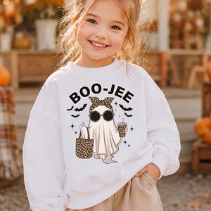 May include: A white long-sleeve sweatshirt featuring a graphic of a ghost wearing a leopard print headband and sunglasses, holding a leopard print tote bag and a drink. The text BOO-JEE is printed above the ghost, accompanied by small bats.