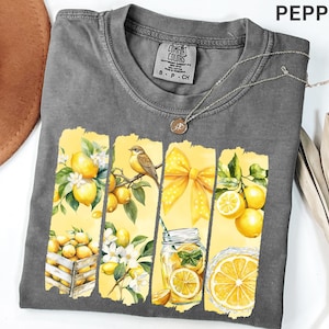May include: A gray Comfort Colors t-shirt with a watercolor design featuring lemons, a bird, and a yellow bow. The design includes a mason jar with a lemon slice and the word "PEPPER" at the top right.
