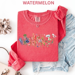 May include: A red long-sleeve shirt with a floral design across the chest. The shirt has a crew neck and is paired with denim shorts. The word "WATERMELON" is printed at the top of the image.