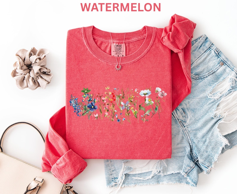 May include: A red long-sleeve shirt with a floral design across the chest. The shirt has a crew neck and is paired with denim shorts. The word "WATERMELON" is printed at the top of the image.