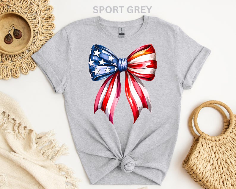 May include: Sport grey t-shirt featuring a watercolor bow design in red, white, and blue, with stars and stripes. The bow is centered on the front of the shirt. The text "SPORT GREY" is at the top.