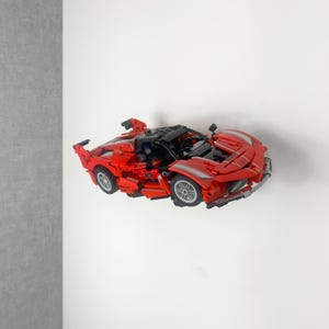 Peut inclure: Une voiture de sport jouet rouge avec des détails noirs et des roues argentées. La voiture miniature présente un design détaillé, avec un intérieur visible et des éléments aérodynamiques. C'est une réplique miniature d'un véhicule réel.