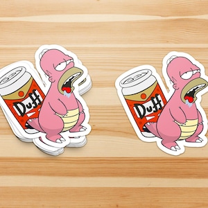 May include: Sticker set featuring a pink cartoon character with a can of Duff beer. The character has a drooling mouth and a tired expression. The Duff beer can is red, white, and gold.