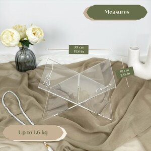 May include: Clear acrylic book stand with a personalized name "Omar" engraved on it. The stand is 11.5 inches tall and 7.48 inches wide. It can hold up to 1.6 kg.