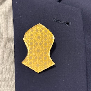 May include: A gold-colored pin in the shape of a mosque with a geometric pattern.