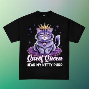 May include: Black t-shirt featuring a cartoon cat wearing a gold crown and a jeweled necklace, sitting on a purple pillow. The text "Queef Queen Hear My Kitty Purr" is printed below the cat.