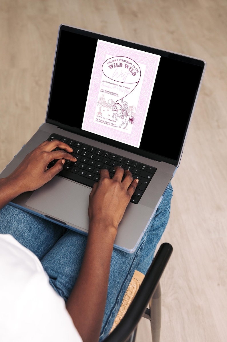 Person using a laptop with the pink “Wild Wild West” invitation displayed on the screen. The image demonstrates easy online editing in Canva, with a cozy workspace setting featuring jeans and a neutral background.