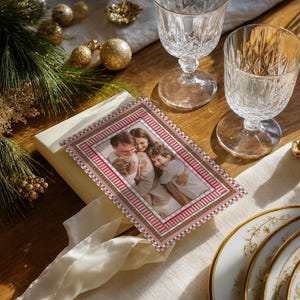 Oh What Fun Christmas card mockup placed on a festive holiday dinner table with crystal glasses, pine greenery, gold ornaments, and ribbon for elegant seasonal styling.