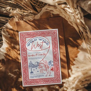 Western-themed party invitation mockup featuring a red and navy “Wild Wild West” design laid on top of a brown envelope and rustic background with cowhide texture, dried wheat, and pampas grass. The invite has a paisley bandana-style border and cowboy illustration, giving it a warm, Western, country vibe perfect for rodeo or cowboy-themed celebrations.