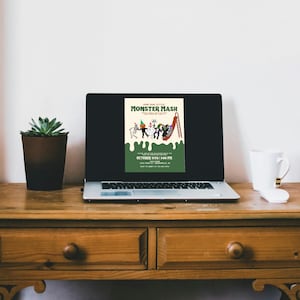 May include: A laptop displays a Halloween-themed poster with the text "Join Our Little Monster Mash." The poster features cartoon monsters and a slide. A potted succulent and a white mug with a black stripe sit on a wooden desk.