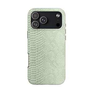 May include: A light green phone case with a textured snakeskin pattern. The case has a black camera module with three lenses and a flash. The case also has a black side button and a black card holder.