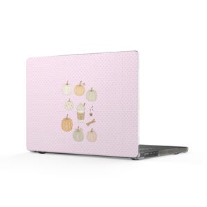 May include: A laptop with a light pink cover featuring a white polka dot pattern. The center displays a collection of illustrations including various pumpkins in shades of orange, white, and green, a coffee cup, cinnamon sticks, and star anise.