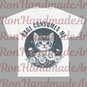 May include: White t-shirt featuring a distressed graphic of a kitten surrounded by flowers, with the text "RAGE CONSUMES ME" in a circular design. The design is in shades of gray, white, and black.
