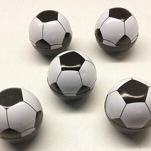 May include: Five black and white mini soccer balls. The balls are about the size of a golf ball.