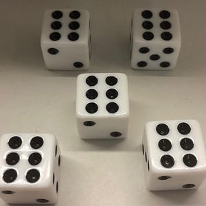 May include: Five white dice with black dots are arranged on a light surface. The dice show various numbers, with the dots arranged in different patterns. The dice are evenly spaced, and the image is well-lit.