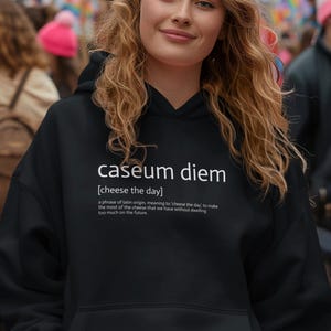 May include: A black hoodie with a white graphic print that says "caseum diem [cheese the day]" and a definition of the phrase.