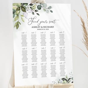 Puede incluir: Un plano de asientos blanco con el texto "Find your seat" y los nombres Ashley & Richard, 28 de marzo de 2026. El gráfico está decorado con detalles florales verdes y blancos y se muestra en un caballete de madera.
